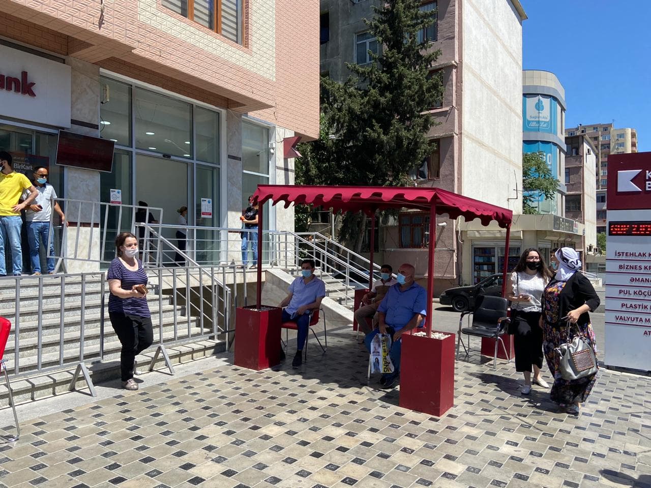 Kapital Bank filialların önündə müştəriləri günvurmadan qoruyur